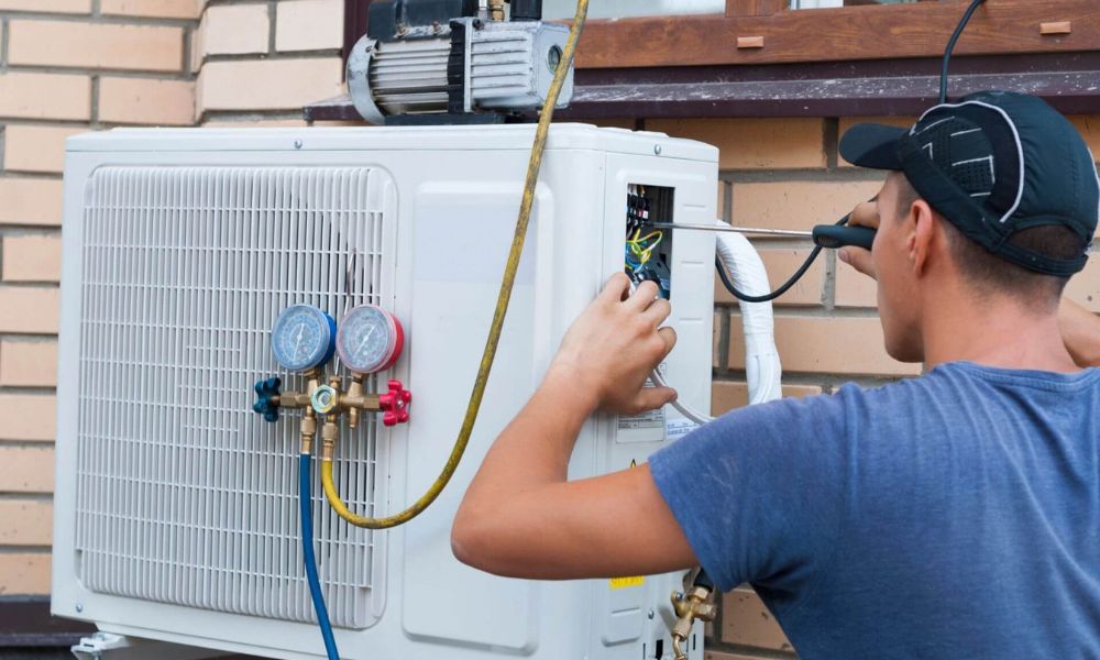 HVAC service technician working on an air conditioning unit with hand tools