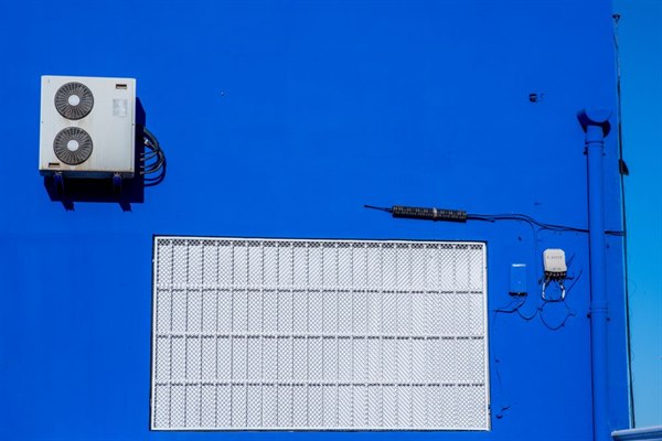 Outdoor condenser unit mounted on a building exterior wall